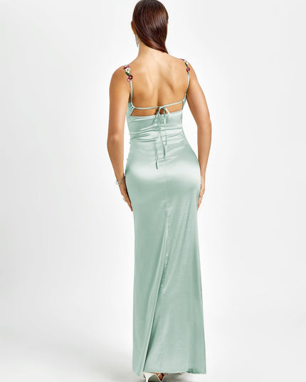 Back view of a light mint green formal maxi dress, highlighting the open back design with tie closures and floral straps.