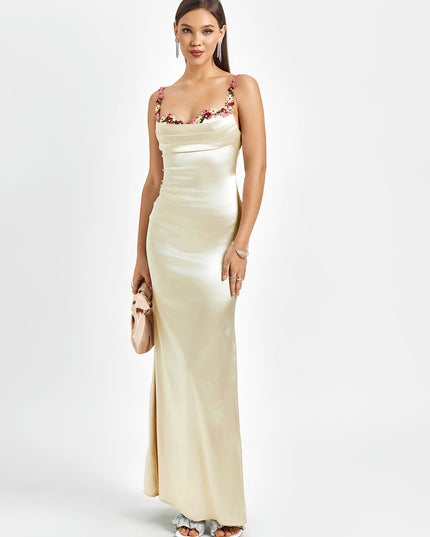 Elegant light champagne satin maxi dress with floral cowl neck and thin straps, paired with a small clutch.
