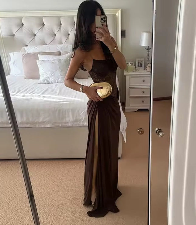 Side view of a woman in a brown off-shoulder lace corset maxi dress with a thigh-high slit, holding a gold clutch.