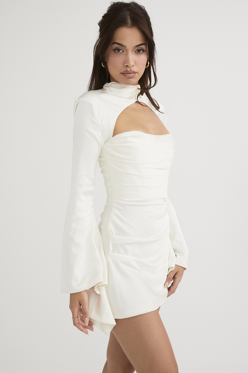 Side profile of the white long sleeve mini dress, showing the elegant cut out and the flow of the satin fabric.
