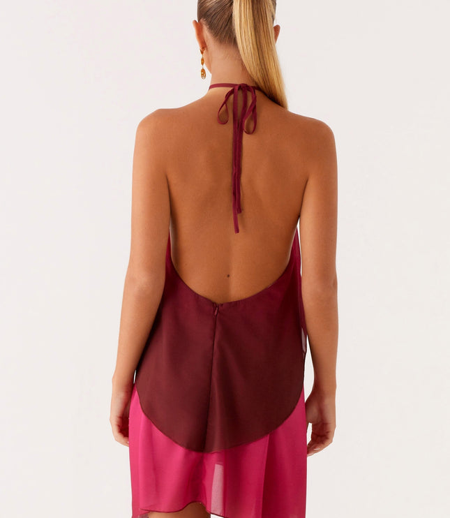 Back view of a women's halter neck ombre layered chiffon mini dress in burgundy and fuchsia, highlighting the open back and tie.