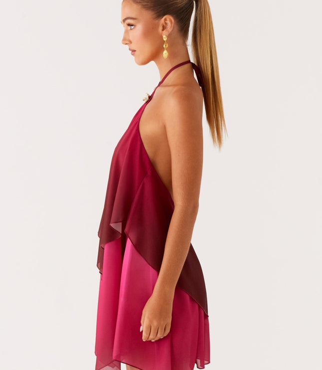 Side profile of a women's halter neck mini dress in burgundy and fuchsia ombre, showcasing the layered chiffon fabric and open back.