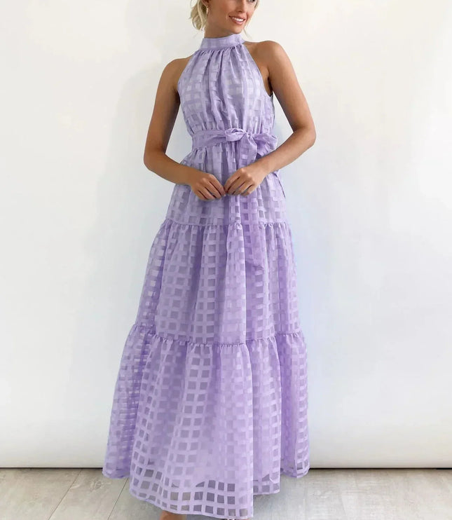Lavender halter neck tiered maxi dress with a subtle checkered pattern, cinched waist, and flowing skirt.