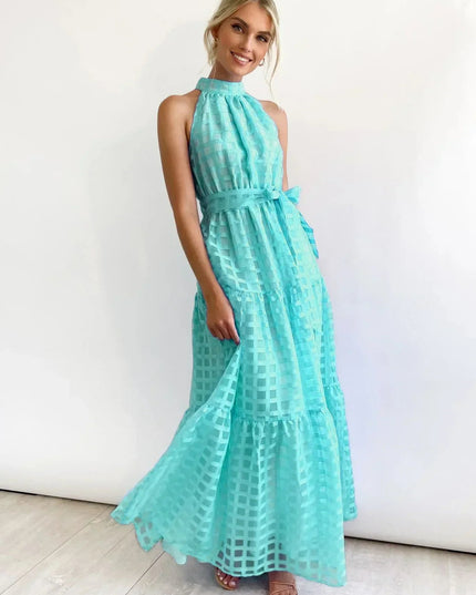 Aqua blue halter neck tiered maxi dress with a checkered pattern and a self-tie belt, twirling gently.