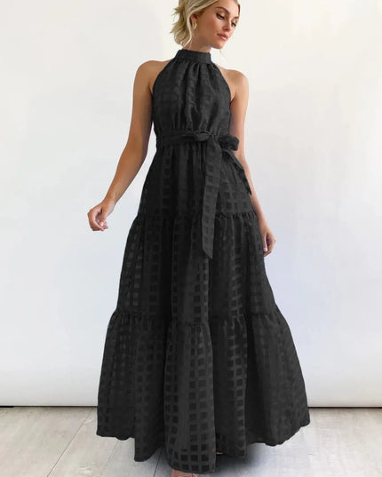 Elegant black halter neck tiered maxi dress, featuring a subtle checkered pattern and a matching waist tie.