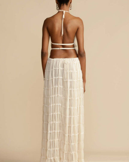 Back view of the women's ivory halter ruffle trim crop top and flowing maxi skirt set, showcasing the open back and skirt details.