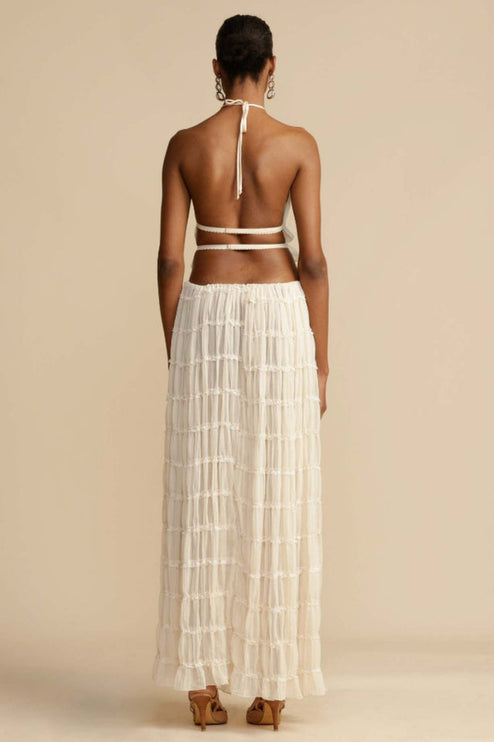 Back view of the women's ivory halter ruffle trim crop top and flowing maxi skirt set, showcasing the open back and skirt details.