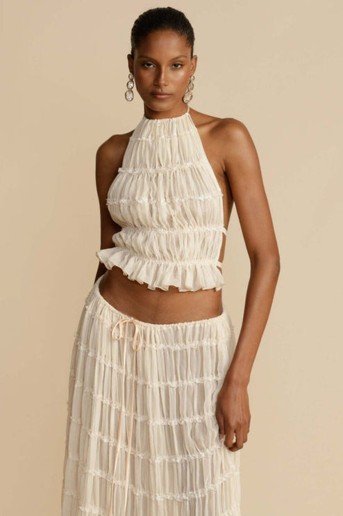 Close-up front view of the women's ivory halter ruffle trim crop top and the top portion of the matching maxi skirt set.