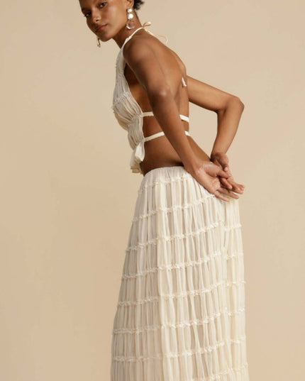 Side profile of the women's ivory halter ruffle trim crop top and maxi skirt set, highlighting the flow of the skirt.
