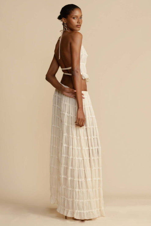 Three-quarter back view of the women's ivory halter ruffle trim crop top and maxi skirt set, showcasing the garment's silhouette.