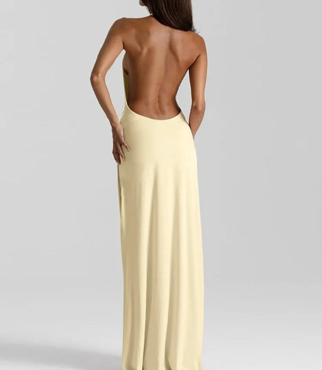 Back view of a pale yellow backless maxi dress with a halter neckline and long flowing skirt.