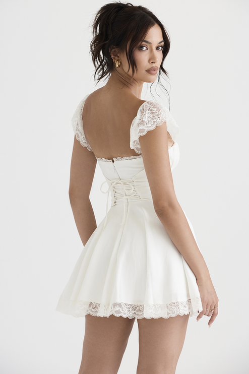 Back view of the white lace cap sleeve mini dress, featuring a corset-style lace-up detail on the back bodice and a full skirt.