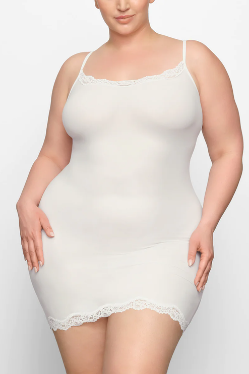 Front view of a plus-size woman wearing an ivory lace trim scoop neck mini slip dress, highlighting the comfortable fit.
