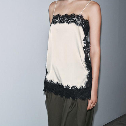 Side view of a women's cream satin camisole mini dress featuring black lace details and delicate straps.