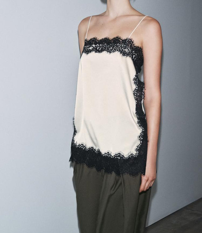 Side view of a women's cream satin camisole mini dress featuring black lace details and delicate straps.