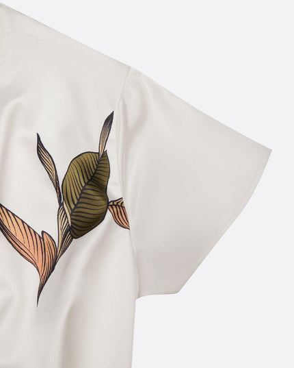 Close-up detail of the short sleeve and leaf print on the white midi wrap dress fabric.