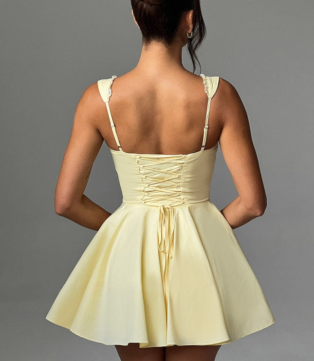 Back view of a women's lemon yellow pintuck mini dress featuring a detailed lace-up corset style back.