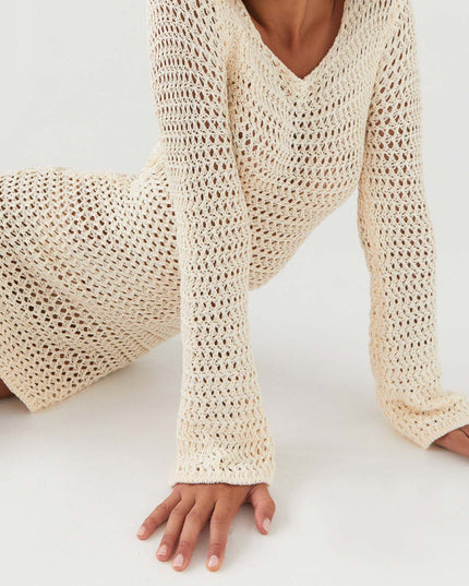 Close-up of a cream long sleeve crochet mini dress with v-neckline, showcasing the intricate knit pattern.