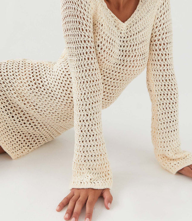 Close-up of a cream long sleeve crochet mini dress with v-neckline, showcasing the intricate knit pattern.