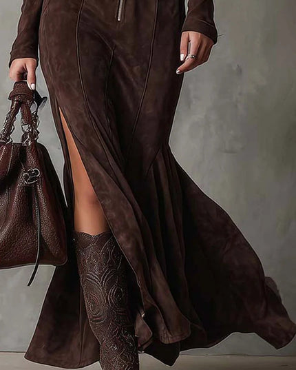 Lower section of the women's brown long sleeve zip up v neck maxi dress, highlighting the flowing skirt, high side slit, and brown patterned boots.