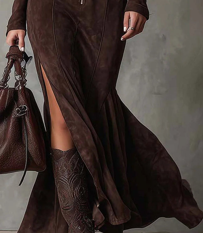 Lower section of the women's brown long sleeve zip up v neck maxi dress, highlighting the flowing skirt, high side slit, and brown patterned boots.