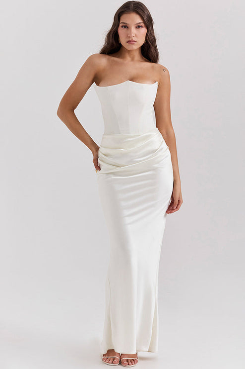 Full-length view of a woman wearing a white off-shoulder bustier draped maxi dress with a sweetheart neckline.