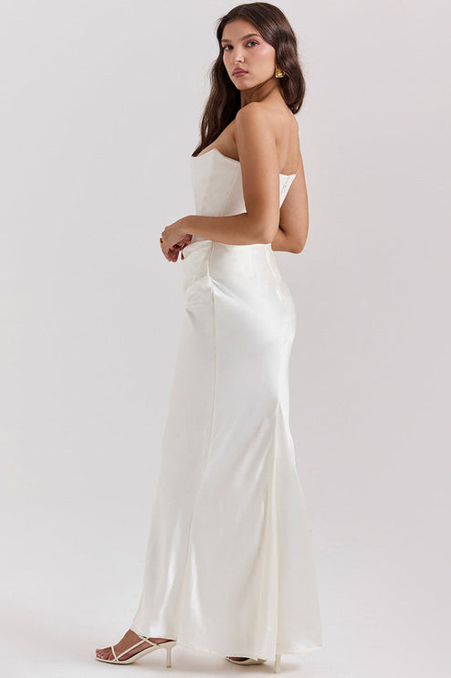 Side view of a white off-shoulder bustier maxi dress, showing the elegant drape and floor-length skirt.