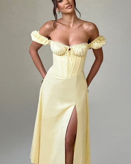 Full-length studio shot of the women's light yellow off-shoulder puff sleeve corset midi dress with a front split.