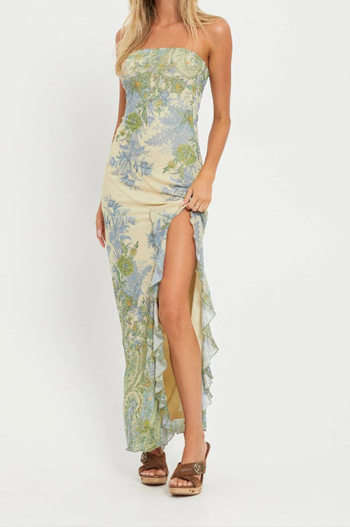 Full-length view of a women's strapless paisley print maxi dress in light yellow with blue and green patterns, featuring a high leg slit with ruffles.