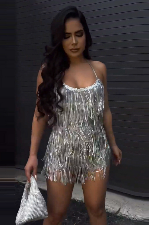 Front view of the women's silver fringe halter neck mini two-piece set, with a silver embellished handbag.