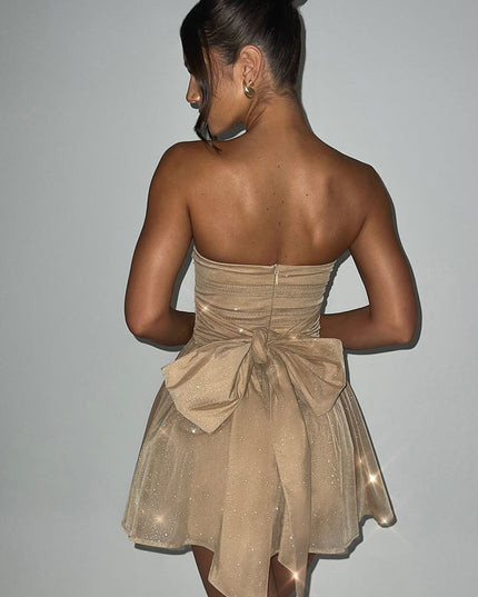 Back view of a gold strapless party dress featuring a large bow detail and subtle sparkle.