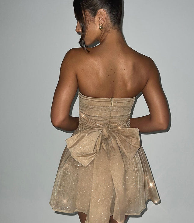 Back view of a gold strapless party dress featuring a large bow detail and subtle sparkle.