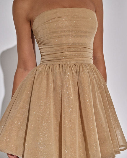 Close-up of the gold sparkle fabric on a strapless mini dress, showing the ruched bodice and flared skirt.