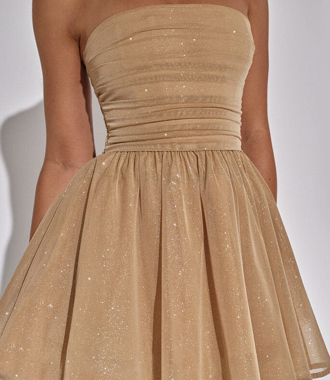 Close-up of the gold sparkle fabric on a strapless mini dress, showing the ruched bodice and flared skirt.