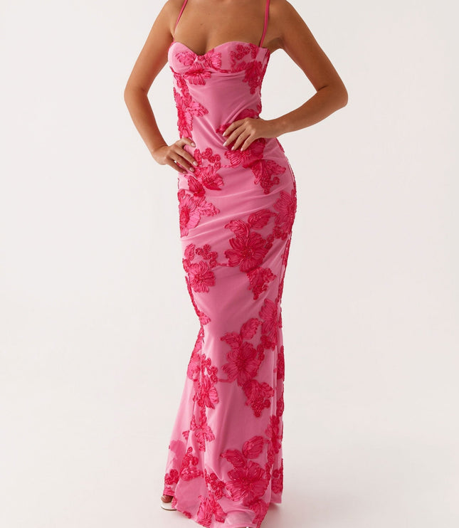 Women's pink floral maxi dress with sweetheart neckline, full body, hands on hips, paired with white heels.