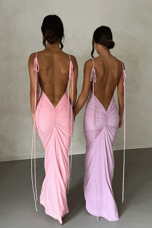 Two women from behind, showcasing a pink and a light purple pleated plunge neck backless maxi dress with tie straps.