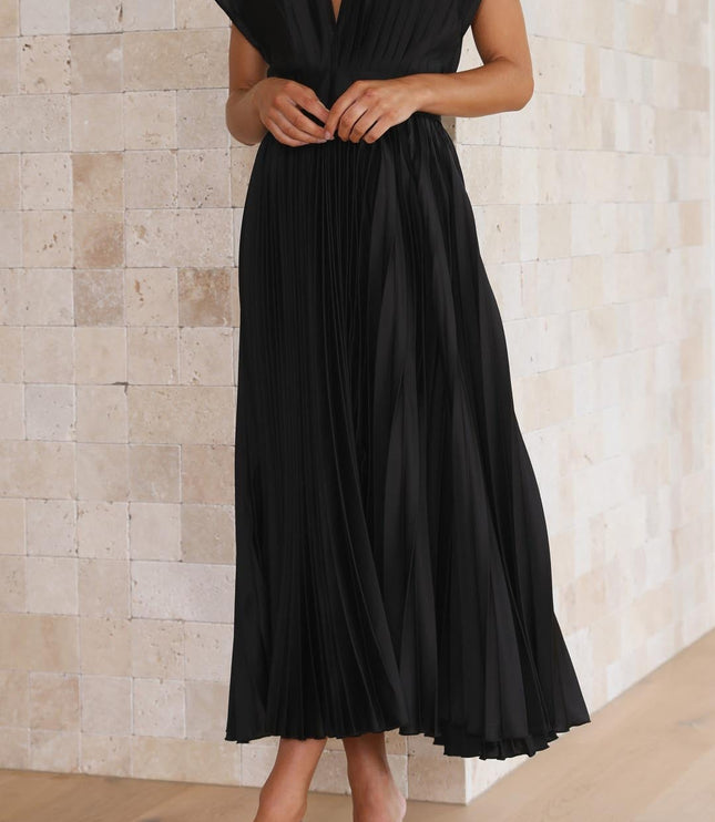 Front detail of the black pleated v-neck midi dress, showing the deep V-neckline and structured short sleeves, with hands clasped.
