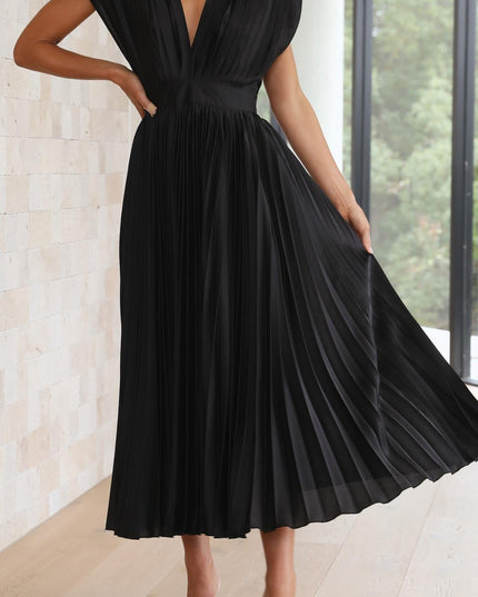 Dynamic view of the black pleated v-neck midi dress, with the model holding out the skirt to show its full pleats and movement.