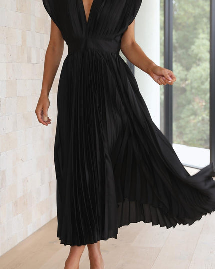 Action shot of the black pleated v-neck midi dress, with the skirt twirling to emphasize its voluminous pleats and flow.