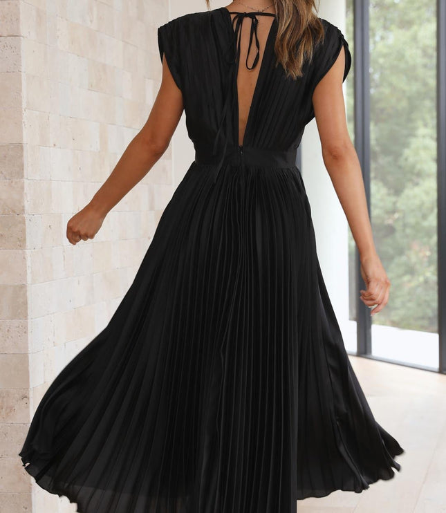 Back view of the black pleated v-neck midi dress, capturing the deep V-back and the movement of the pleated skirt as the model turns.