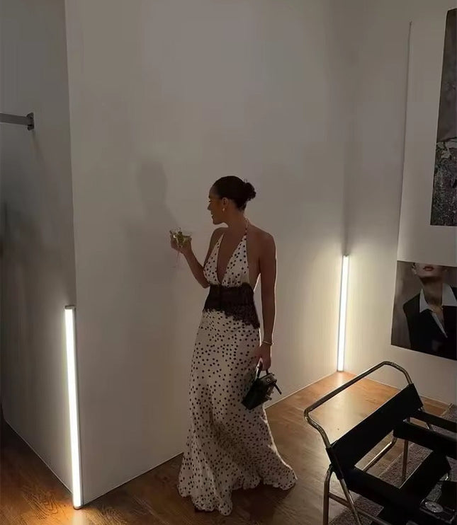 Women's polka dot halter neck lace maxi dress in a room setting, showing the full length of the dress with black lace detail.