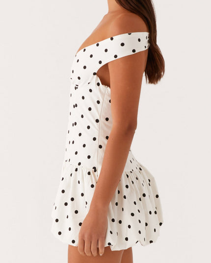 Side profile of white polka dot off-shoulder mini dress showing ruched bust and bubble hem design.