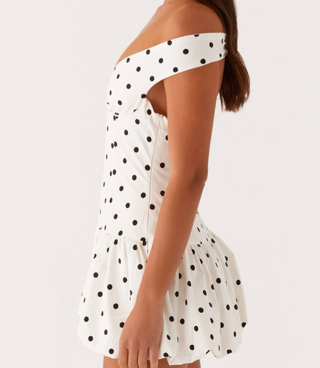 Side profile of white polka dot off-shoulder mini dress showing ruched bust and bubble hem design.