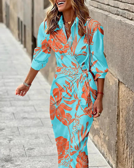 Light blue women's long sleeve V-neck midi dress with an orange tropical leaf print and a knotted detail.