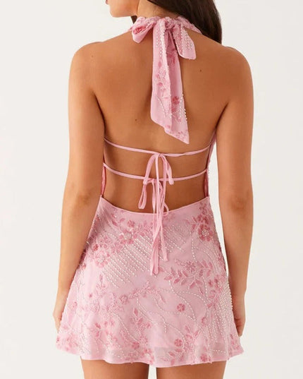 Back view of pink floral halter cowl neck mini dress with tie closure and open back.
