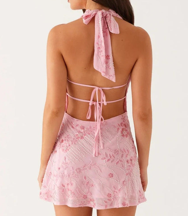 Back view of pink floral halter cowl neck mini dress with tie closure and open back.
