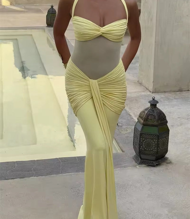 Front view of a women's pastel yellow prom dress, featuring a halter neckline, ruched details, and a flowing maxi skirt, in an outdoor setting.