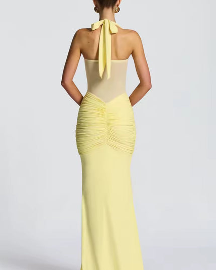 Back view of a women's light yellow halter neck ruched mesh maxi dress, highlighting the tie-back detail and gathered ruching on the rear.