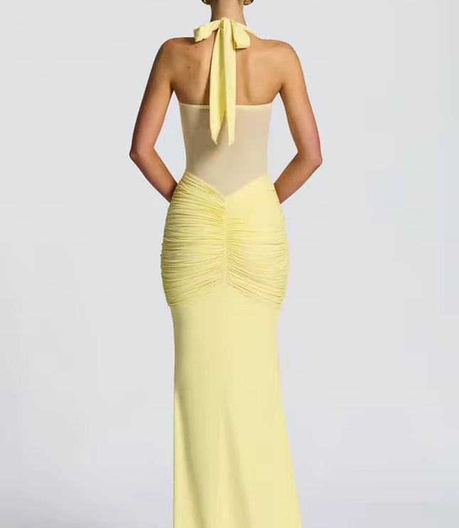 Back view of a women's light yellow halter neck ruched mesh maxi dress, highlighting the tie-back detail and gathered ruching on the rear.