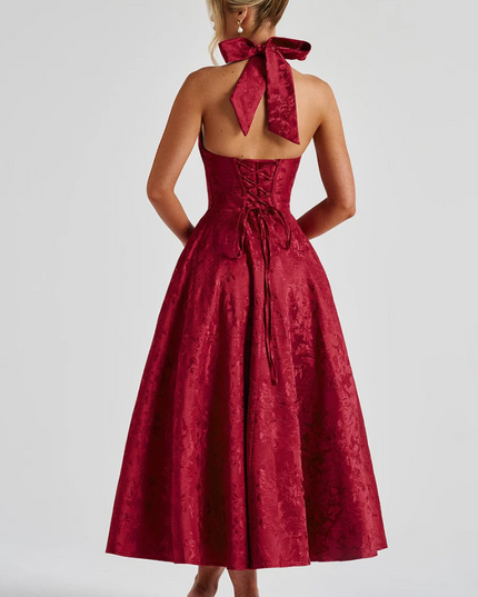 Back view of a red jacquard midi dress, showing the halter bow tie and corset lacing.